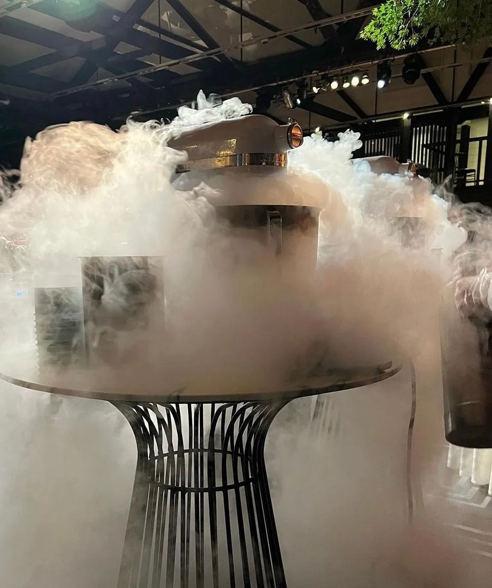 Nitrogen fog pouring off a round table around a mixer at an indoor event