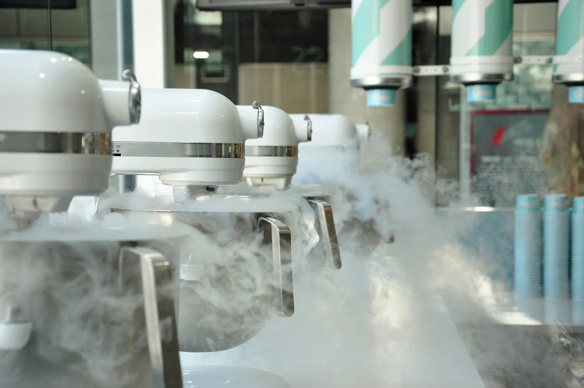 A row of white mixers with nitrogen fog spilling from the bowls